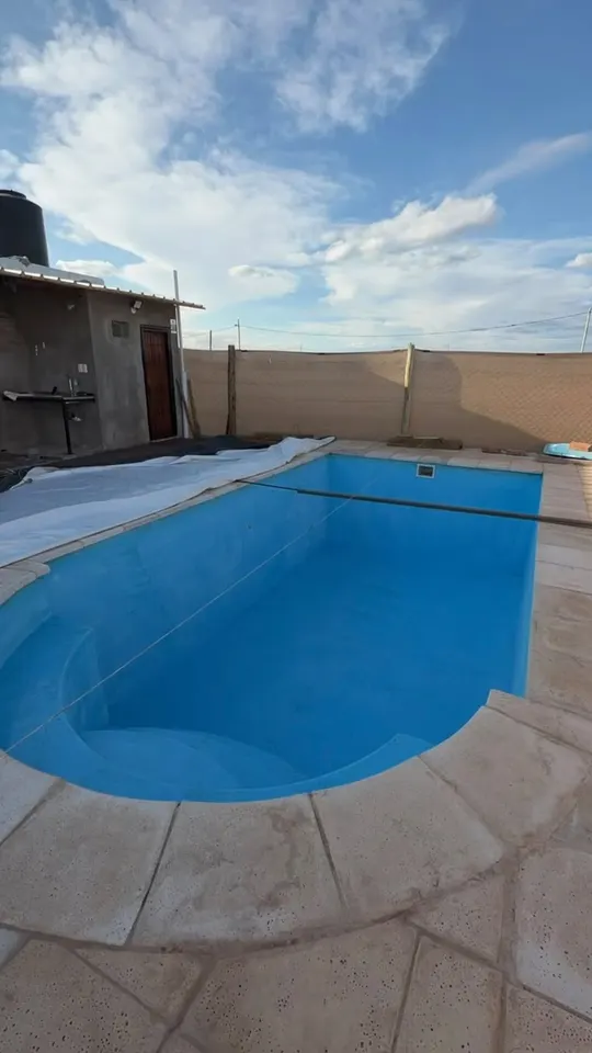 Piscina recién pintada de azul, vacía y lista para llenar, con el cielo de la tarde detrás